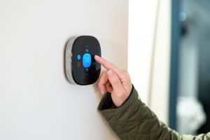 Person setting the temperature on a smart thermostat